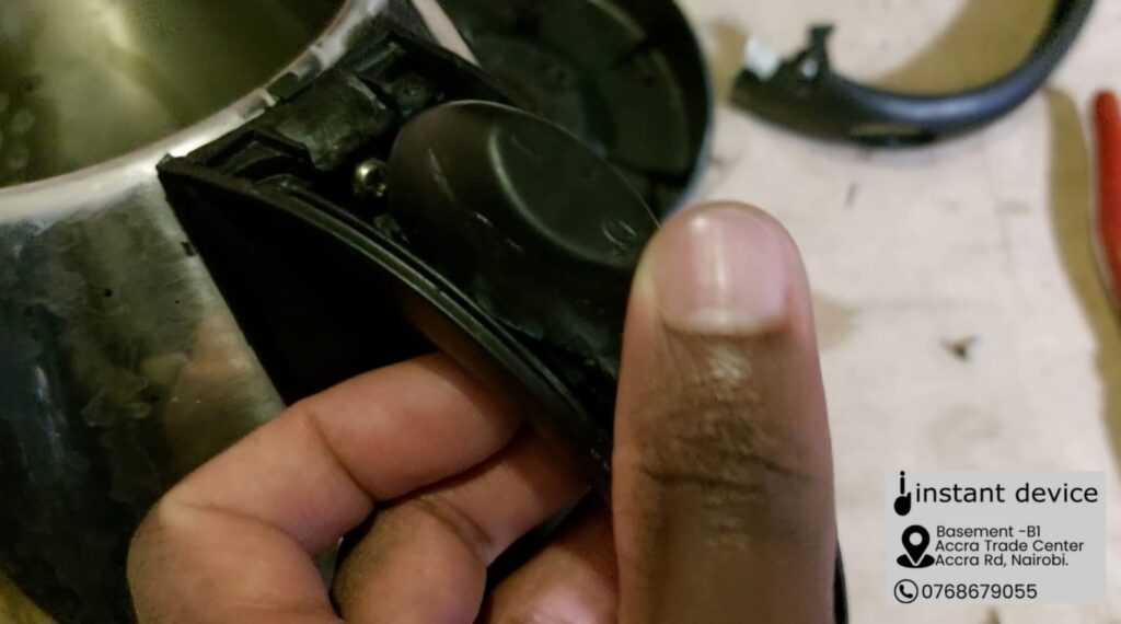 Exposed On/Off switch on a cordless electric kettle with the handle cover on the foreground.